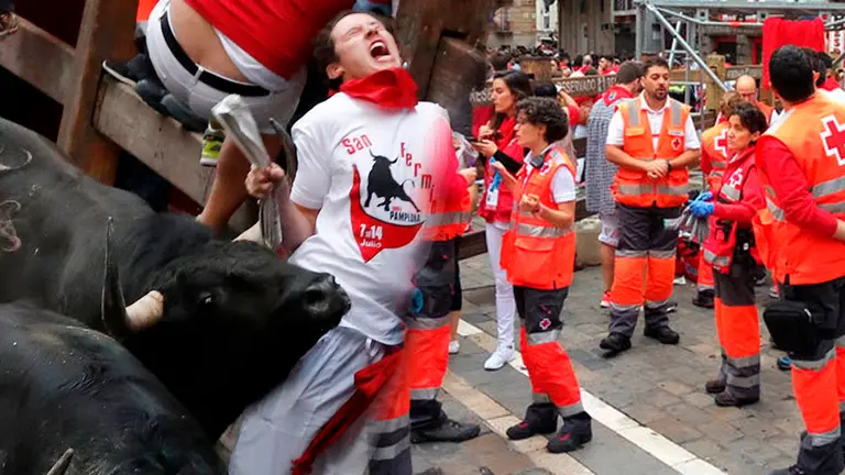Un corredor es alcanzado por un toro en la curva de la Estafeta junto a una imagen del dispositivo sanitario del encierro de Sanfermines NAVARRACOM