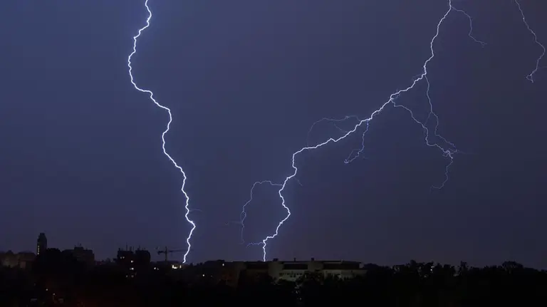 Imagen de dos rayos cayendo cerca de un barrio con bloques de pisos durante una noche con tiempo marcado por las tormentas ARCHIVO