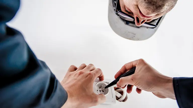 Un electricista trabajando en un enchufe ARCHIVO