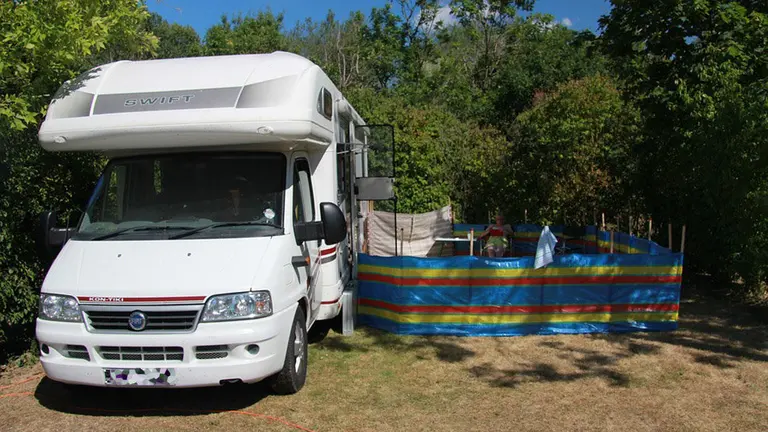 Imagen de una mujer sentada en una tumbona junto a una autocaravana estacionada en un camping ARCHIVO