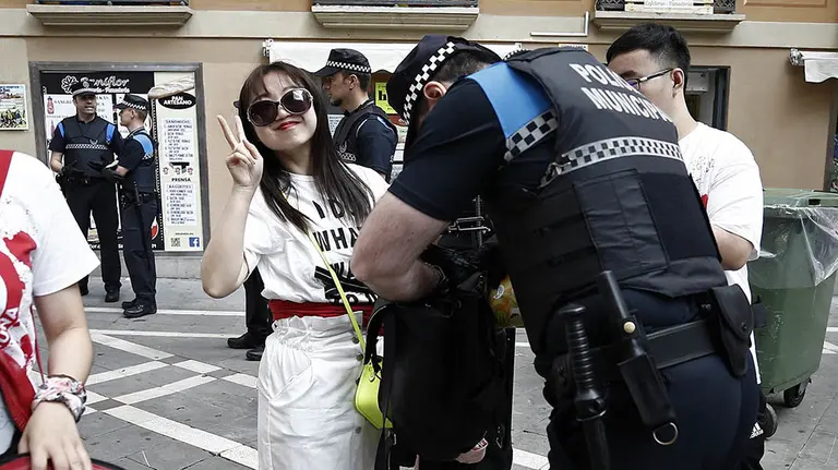 GRAF4610. PAMPLONA (ESPAÑA), 06/07/2018.- Efectivos de la Policía Municipal de Pamplona revisan las mochilas de los que acceden a la Plaza del Ayuntamiento, donde no se pueden pasar ni botellas de vidrio, huevos o cualquier objeto que pudiera poner en peligro la integridad de los que quieren ver el lanzamiento del tradicional "txupinazo" desde el balcón de la casa consistorial, con el que da comienzo oficialmente las fiestas de San Fermín 2018.- EFE/Jesús Diges