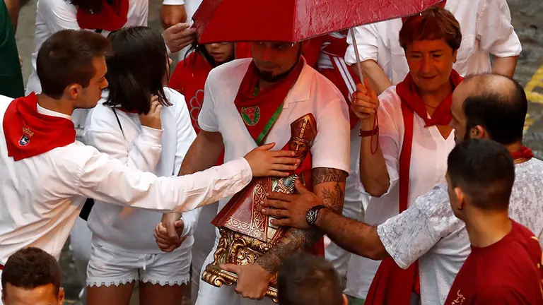 GRAF5858. PAMPLONA (ESPAÑA), 08/07/2018.-Varios mozos besan la imagen de San Fermín, antes de ser colocada en la hornacina de la cuesta de Santo Domingo para pedir su protección en la carrera, momentos antes de que los toros de la ganadería de José Escolar Gil (Ávila), protagonicen hoy el segundo encierro de los Sanfermines 2018.- EFE/Villar López
