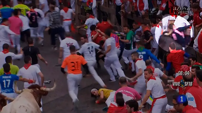 Momento en el que un toro golpea con el cuerno en el cuello a un  mozo en telefónica