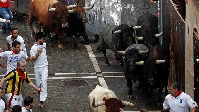 Los toros de la ganadería sevillana de Miura enfilan la calle Estafeta tras pasar la curva de Mercaderes durante el octavo y último encierro de los Sanfermines 2018, el más rápido de las fiestas con 2 minutos y 12 segundos de duración, en el que, según el primer parte médico, no hay heridos por asta. EFE/Villar López