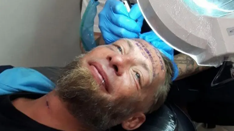 Tomek, mientras es tatuado en la frente