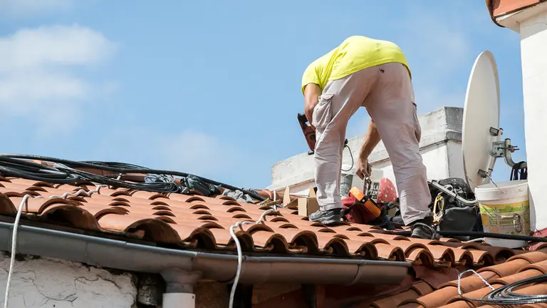 Un operario trabaja en la instalación del cable de fibra óptica en un tejado de Pamplona (11). IÑIGO ALZUGARAY
