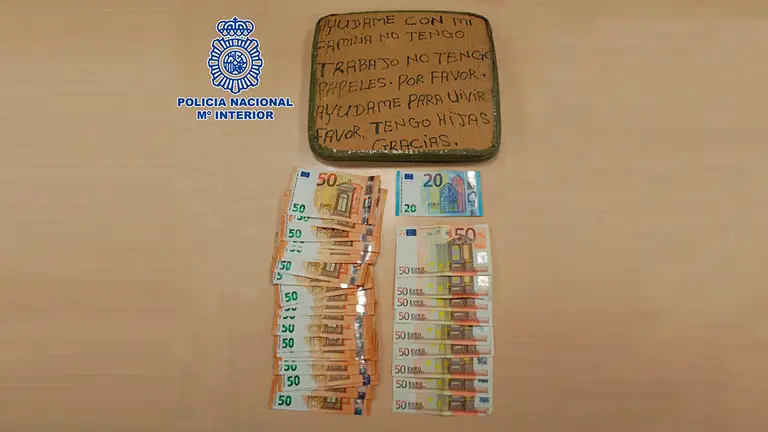 Dinero en efectivo hallado en su domicilio junto a un cartel que el hombre usaba para pedir dinero POLICÍA NACIONAL