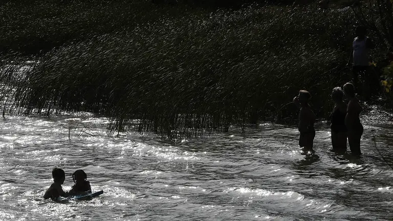 Un grupo de jóvenes disfrutan de un baño para combatir el calor en la balsa de La Morea, en la localidad navarra de Beriáin, antes de que una pequeña tormenta atravesara la zona. EFE/Jesús Diges