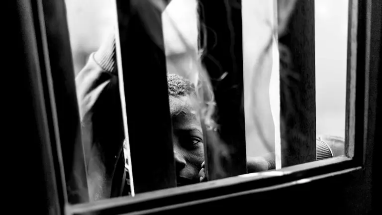 Un niño talibé observa a través de una ventana con rejas. La educación de los talibés está basada en amenazas, violencia y castigos. Los niños sufren desde golpes y latigazos hasta la privación de libertad por varios días o semenas y en ocasiones atados con cuerdas y grilletes. IÑIGO ALZUGARAY