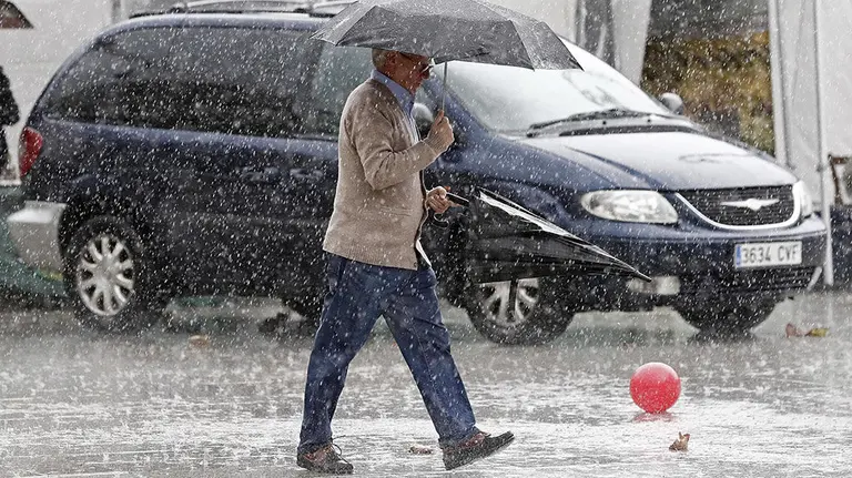 -FOTODELDIA- GRAF6486. PAMPLONA, 14/10/2018.- Una persona pasea por la Plaza del Castillo de Pamplona donde las nubes que amenazaban con lluvia han dejado un fuerte aguacero y rachas de viento que afectan a Navarra desde que a media mañana ha comenzado a notarse la influencia del ciclón tropical Leslie. EFE/Jesús Diges