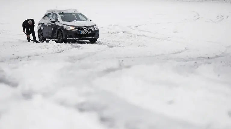 Un conductor intenta liberar su vehiculo quitando con una pala la nieve de la carretera en Roncesvalles. El cielo estará hoy en Navarra cubierto tendiendo a nuboso y con intervalos nubosos y posibles brumas y bancos de niebla matinales en zonas altas, con la cota de nieve que ascenderá desde los 800 metros de la mañana a los 1.200 metros por la tarde.- EFE/Jesús Diges