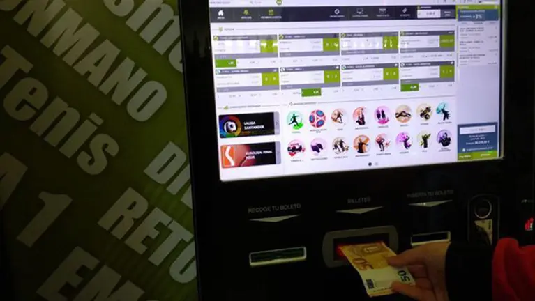Imagen de un joven introduciendo un billete de 50 euros en una máquina de apuestas deportivas. PINTEREST