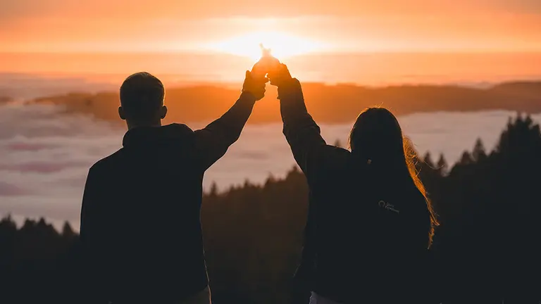 Dos personas celebran su vida sobre un atardecer en una monta&ntilde;a. ERIC WARD. 