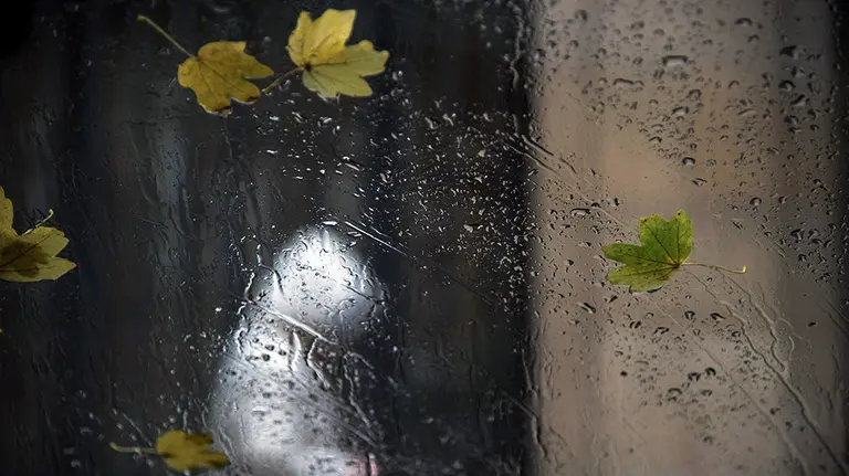 Una persona camina con una capucha en Pamplona durante un día otoñal marcado por el tiempo frío, el viento y las lluvias. EFE / Iñaki Porto