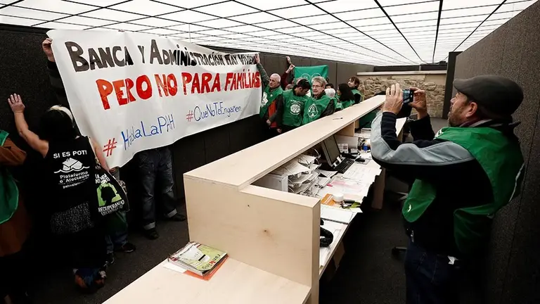 GRAFCAV566. PAMPLONA, 20/12/2018.- Un grupo de miembros de la Plataforma de Afectados por la Hipoteca (PAH) han entrado hoy en la Oficina de Vivienda del Ayuntamiento de Pamplona, en la calle Descalzos, donde han desplegado una pancarta con el lema "Banca y Administración, hay vivienda, pero no para familias". Los participantes en esta acción de protesta llevaban chalecos verdes en los que podía leerse "ImPAHrables. Stop Desahucios" y han cantado varios villancicos con letras alusivas al problema de la vivienda. EFE/ Jesus Diges