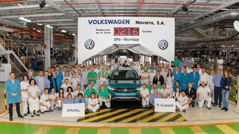 Varios empleados implicados en la construcción del nuevo modelo de coche en Volkswagen Navarra junto al vehículo recién armado. VOLKSWAGEN NAVARRA