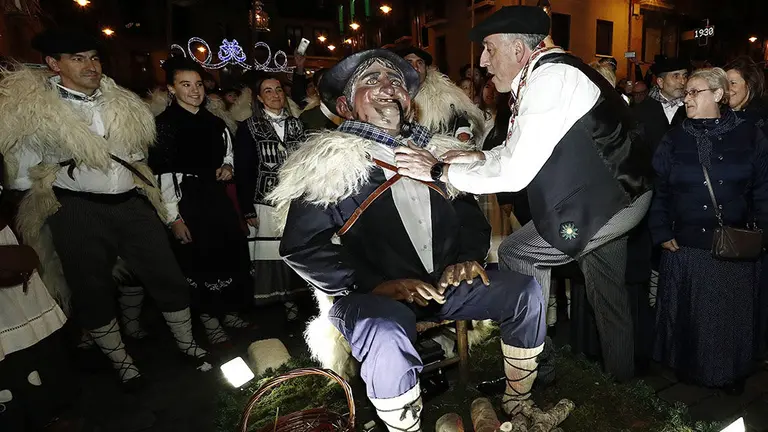 GRAF1085. PAMPLONA (NAVARRA) 24-12-2018. Miles de personas cargadas de ilusiones, adultos, jóvenes y niños, han recibido esta tarde en Pamplona a Olentzero, al que han acompañado en su recorrido por la ciudad y en el homenaje que le ha tributado el Ayuntamiento. Como sucede desde 2015, el viejo carbonero sido recibido por el alcalde en la plaza consistorial. Allí, Joseba Asiron (d), acompañado de concejales y de la banda de música municipal La Pamplonesa, ha impuesto a Olentzero un gran pañuelo de cuadros azul y blanco, típico de su atuendo, con el escudo de la cuidad en reconocimiento y recuerdo. EFE/Jesús Diges
