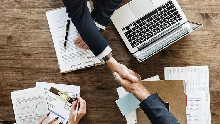 Dos personas se estrechan la mano tras firmar un contrato de trabajo ARCHIVO