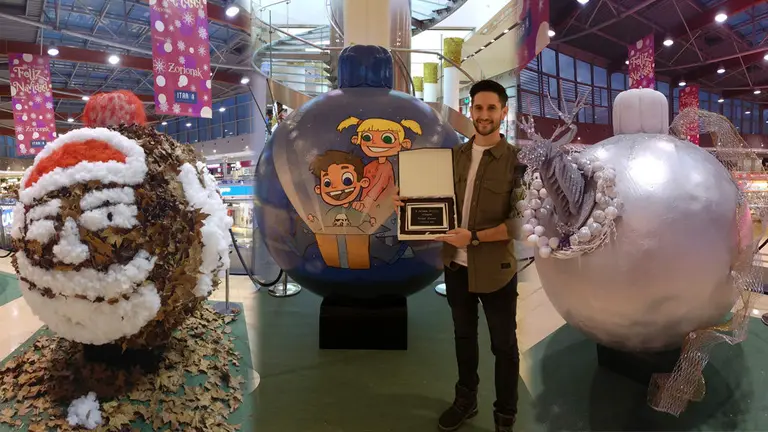 El pamplonés Mariano Eliceche posa con su macrobola de Navidad que le ha valido para ganar el X certamen artístico del Centro Comercial Itaroa, junto a otros trabajos finalistas IMÁGENES CEDIDAS