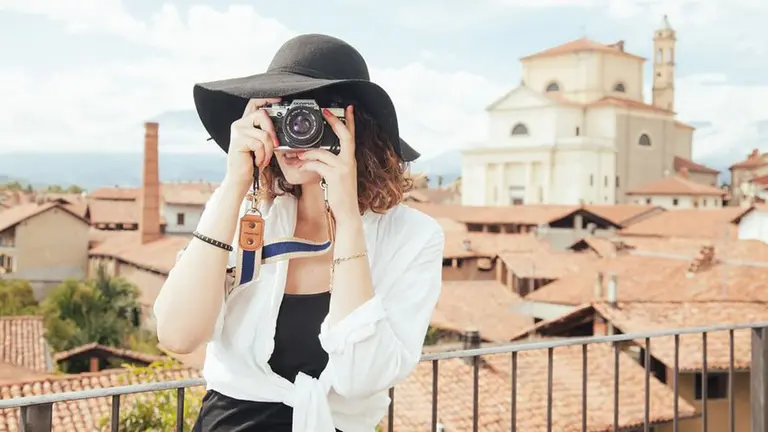 Una mujer toma una fotografía durante una visita a un pueblo ARCHIVO