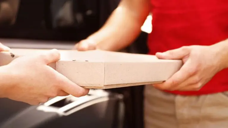 Un hombre le entrega a otro una caja de pizza ARCHIVO