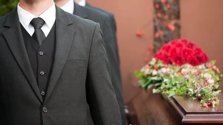 Varias personas aguardan en un velatorio junto a un ataud. ARCHIVO