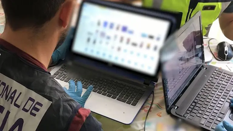 Un agente de la policía adscrito a un grupo que estudia delitos cibernéticos inspecciona el ordenador de un detenido POLICÍA NACIONAL