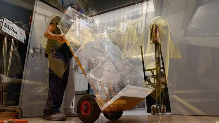 Fotomontaje de un hombre preparando las urnas para las elecciones junto a una procesión de Semana Santa. NAVARRACOM