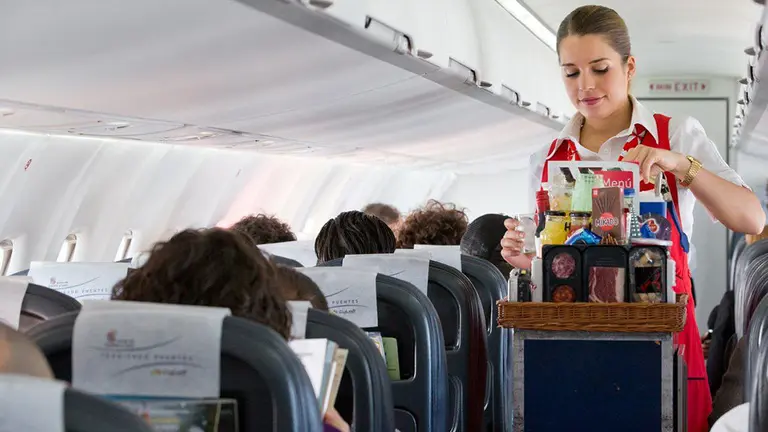 Imagen de una tripulante de cabina atendiendo a los pasajeros de un avión durante un vuelo azafata ARCHIVO
