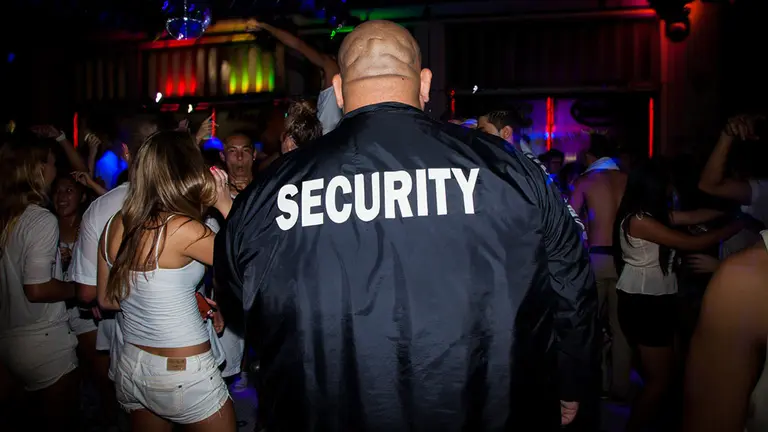 Imagen de un portero de discoteca junto a unos jóvenes que disfrutan de una fiesta bailando ARCHIVO