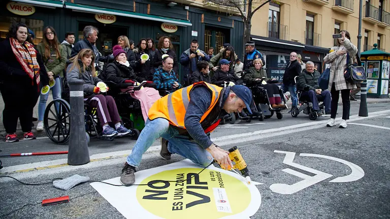 Cocemfe Navarra lleva a cabo la colocación de la primera pegatina dentro de la campaña para respetar la reserva de plazas de aparcamiento para personas con discapacidad. IÑIGO ALZUGARAY