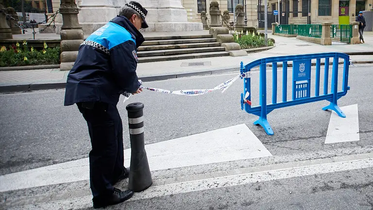 Un agente de la Policía Municipal acordona con una valla una de las plazas de aparcamiento reservada para personas con discapacidad en el Paseo Sarasate de Pamplona, junto al Monumento a los Fueros. IÑIGO ALZUGARAY