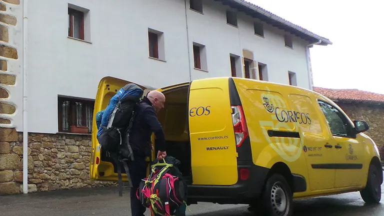 Un empleado de Correos entrega en un albergue del camino de Santiago a su paso por Navarra las mochilas transportadas con el servicio dirigido a peregrinos CORREOS