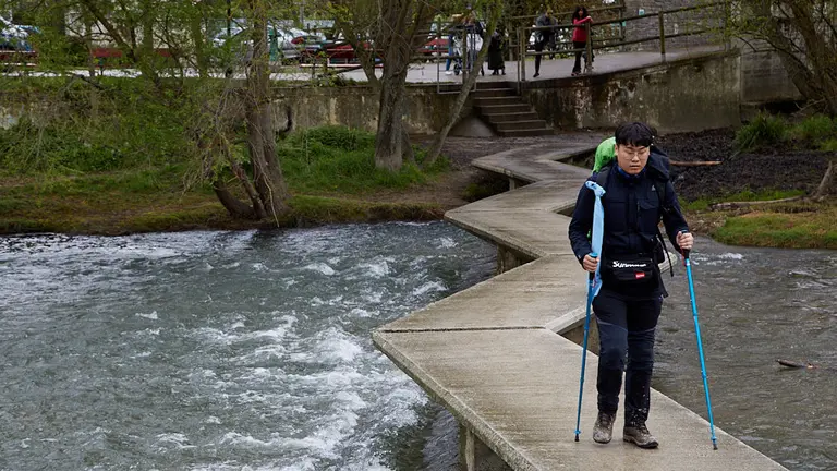 Peregrino del Camino de Santiago cruza el río Arga por una pasarela de la Magdalena. IÑIGO ALZUGARAY