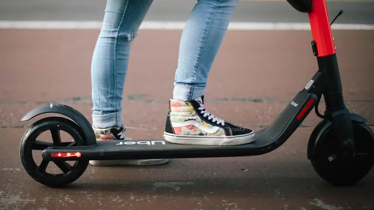 Una persona sobre un patinete eléctrico de Uber UBER