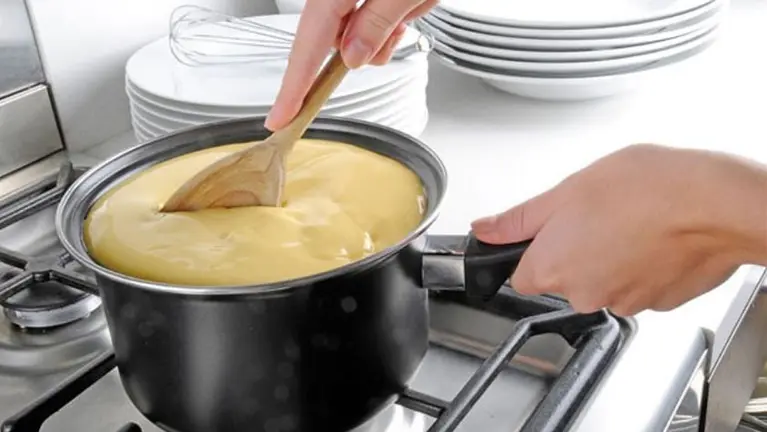 Imagen de una mujer cocinando unas natillas en una olla. ARCHIVO