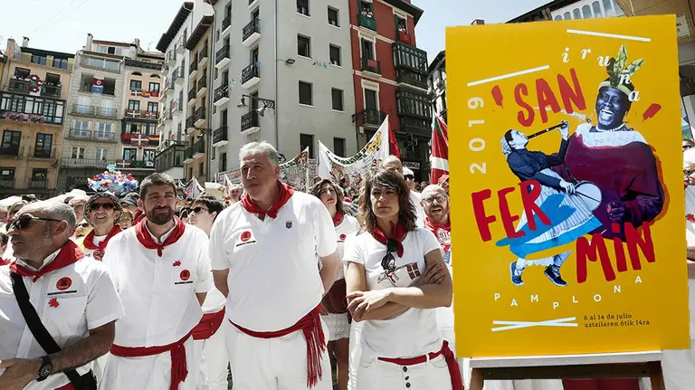 Los concejales de Bildu Joxe Abaurrea, Aritz Romeo (segundo por la izquierda) y Madier Beloki (primera por la derecha), flanquean al alcalde Joseba Asirón en un acto durante los pasados Sanfermines, junto a una imagen del cartel encabezado por el rostro de una de las candidatas de Bildu al Congreso. NAVARRA.COM