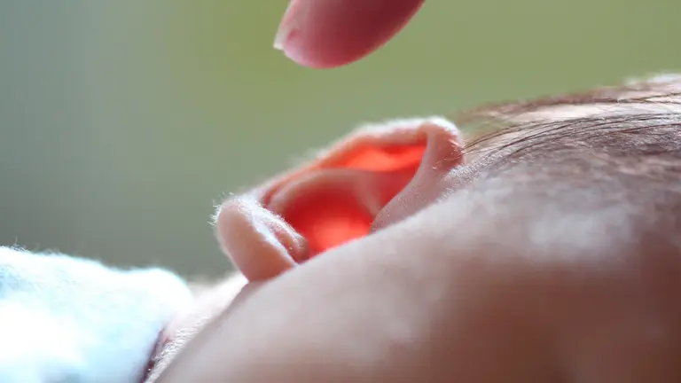 Una madre se acerca a su bebé para tocarle la oreja. ARCHIVO