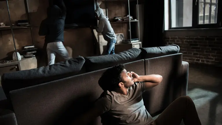 Un joven se esconde detrás de un sofá y llama a la policía mientras una pareja de ladrones asalta su piso y trata de robar varios objetos de valor ARCHIVO