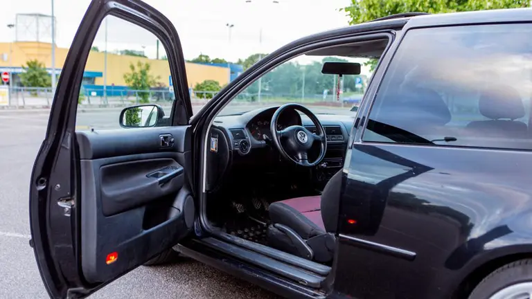 Imagen de un coche estacionado con la puerta abierta mientras el conductor se baja para hacer un breve recado ARCHIVO