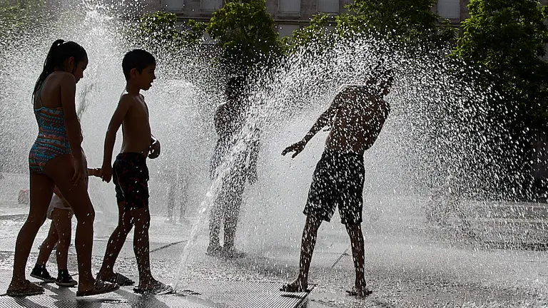 Unos niños juegan en la 'fuente de chorros' de la Plaza de Yamaguchi durante la primera ola de calor del verano en Pamplona. IÑIGO ALZUGARAY