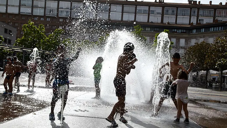 Unos niños juegan en la 'fuente de chorros' de la Plaza de Yamaguchi durante la primera ola de calor del verano en Pamplona. IÑIGO ALZUGARAY