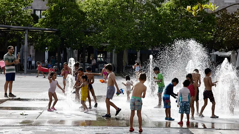 Unos niños juegan en la 'fuente de chorros' de la Plaza de Yamaguchi durante la primera ola de calor del verano en Pamplona. IÑIGO ALZUGARAY