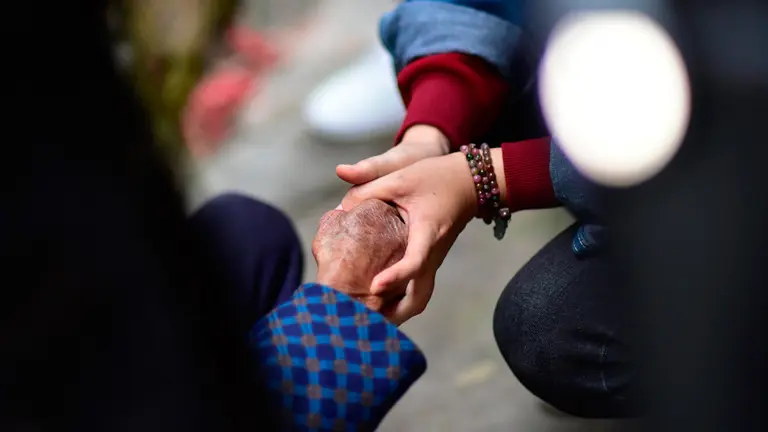 Una joven agarra la mano de una persona mayor. ARCHIVO