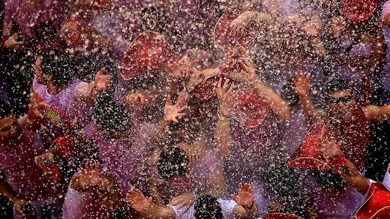 Varios jóvenes aguardan la llegada del agua desde los balcones de Pamplona tras el tradicional Chupinazo. AFP / REUTERS
