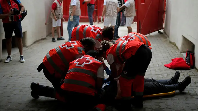 An injured reveller is helped by medical staff during the first running of the bulls at the San Fermin festival in Pamplona, Spain, July 7, 2019. REUTERS/Jon Nazca - RC1C06EFF2A0