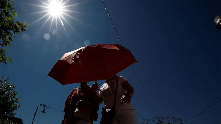 GRAFCAV6436. PAMPLONA (NAVARRA), 12/07/2019.- Dos mujeres se protegen con un paraguas del sol, en una jornada donde a falta de dos días para que finalicen los Sanfermines del 2019, las altas temperaturas son la nota característica del día. EFE/ Jesús Diges