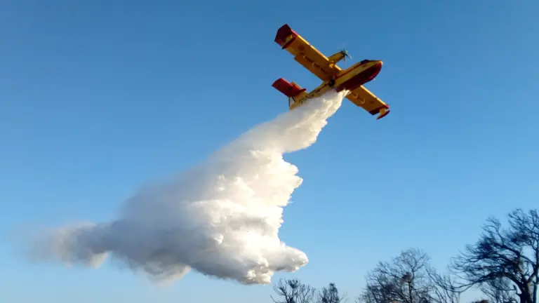 Un avión Foca realiza una descarga de agua sobre los árboles afectados por el incendio. CEDIDO