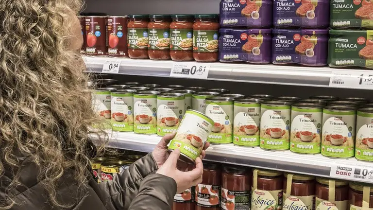 Una mujer observa el etiquetado de un producto en un supermercado EROSKI
