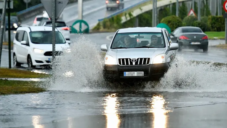 Varios coches hacen frente a la lluvia almacenada en la carretera de acceso a La Morea. PABLO LASAOSA (2)